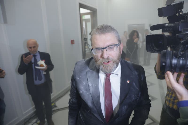 Far-right Polish lawmaker Grzegorz Braun from Konfederacja party interacts with the media after using a fire extinguisher to put out Hanukkah candles at the parliament in Warsaw