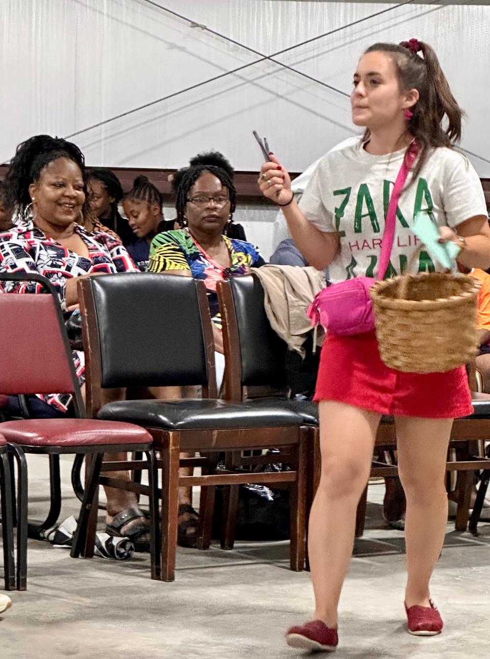 Caroline Grogan passes out pens and paper to the audience to “collect their dreams” during a performance of "Dream a Little Dream," in Camden, Alabama, on July 2, 2023.