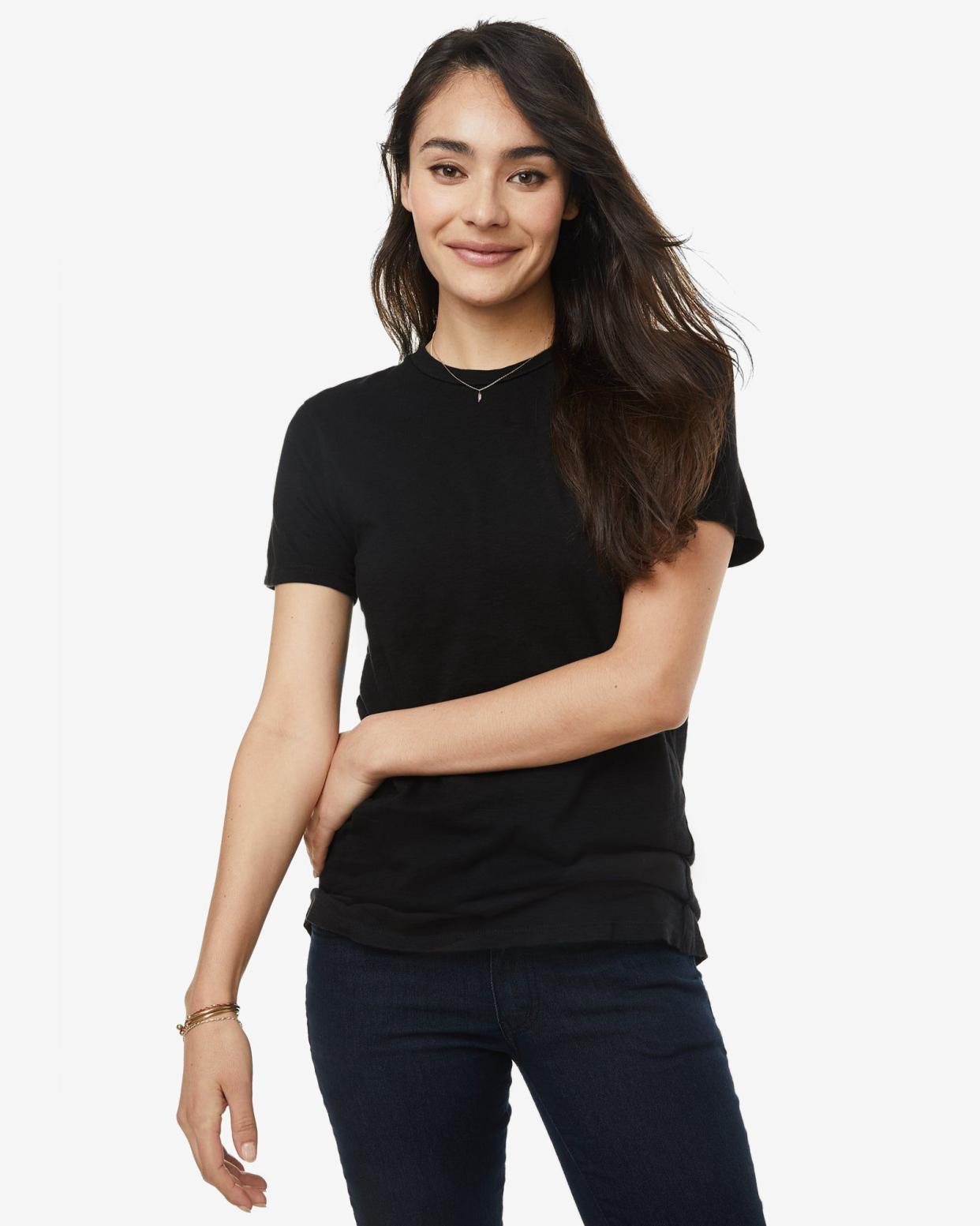 Young woman with long dark hair wearing black tee and black trousers.