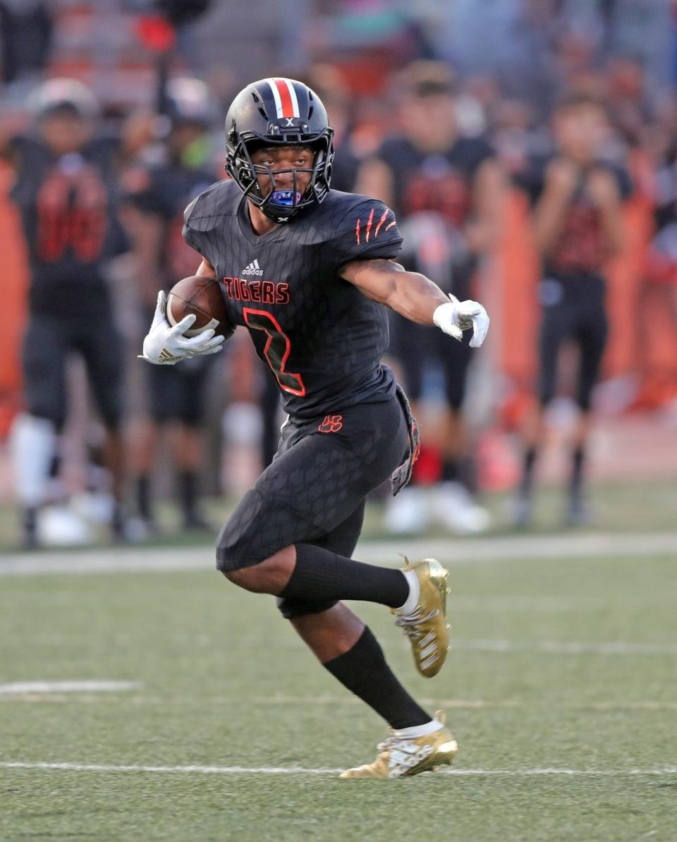 Belleville Tigers' Andre Seldon runs by Dearborn Pioneers defenders during the first half Friday, Sept. 13, 2019 at Belleville high school.