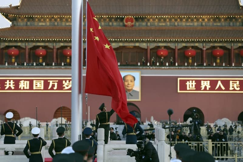 A member of the Chinese People's Liberation Army raises the Chinese flag on its mast during the first national flag raising ceremony in 2018 at Tiananmen Square in Beijing, China, 01 January 2018. Photo: ---/TPG via ZUMA Press/dpa ---/TPG via ZUMA Press/dpa