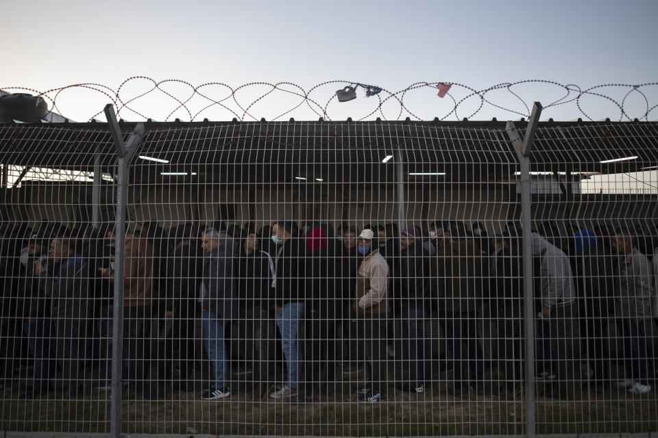 FILE - Palestinian workers line up while waiting at the Palestinian side of Erez crossing to cross into Israel, in the town of Beit Hanoun, northern Gaza Strip, Sunday, March. 27, 2022. The White House says Palestinians are entitled to the same measure of "freedom, security and prosperity" enjoyed by Israelis, but when President Joe Biden visits the region this month he will have few accomplishments to point to. (AP Photo/Khalil Hamra, File)