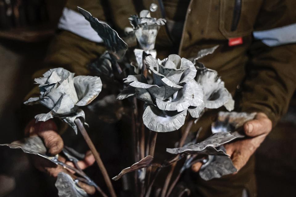 Viktor Mikhalev shows roses transformed from weapons and ammunition into flowers of war in his hands in a workshop in his house in Donetsk, Russian-controlled Donetsk region, eastern Ukraine, Saturday, March 4, 2023. Mikhalev, trained as a welder, lives and works in a house whose fence and door are decorated with forged flowers and grapes. (AP Photo/Alexei Alexandrov)