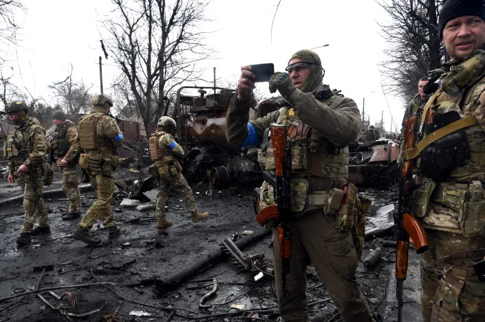 A Ukrainian soldier takes pictures with a cellphone of the wreckage of war in Bucha.