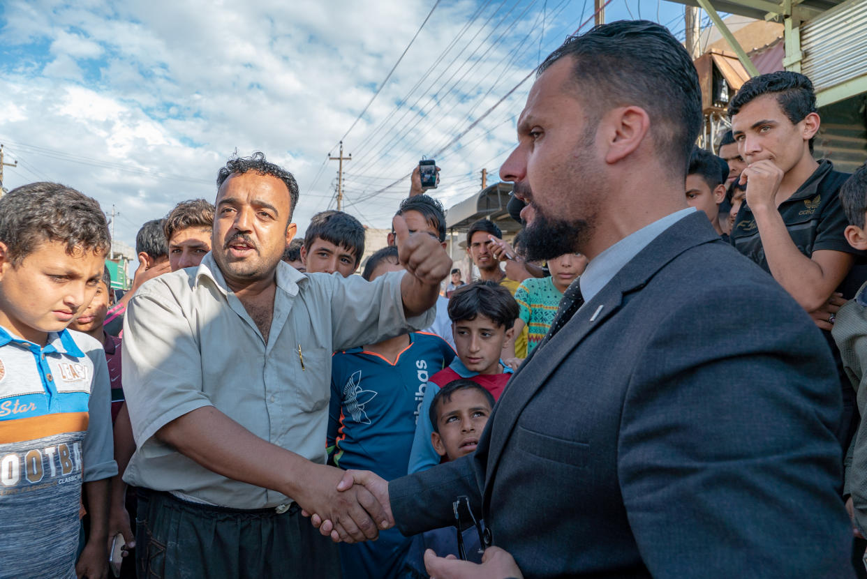 Abdullah shakes hands with Fizza Ali as a crowd gathers to hear a debate between the candidate and his prospective voters. (Photo: Shawn Carrié for Yahoo News)