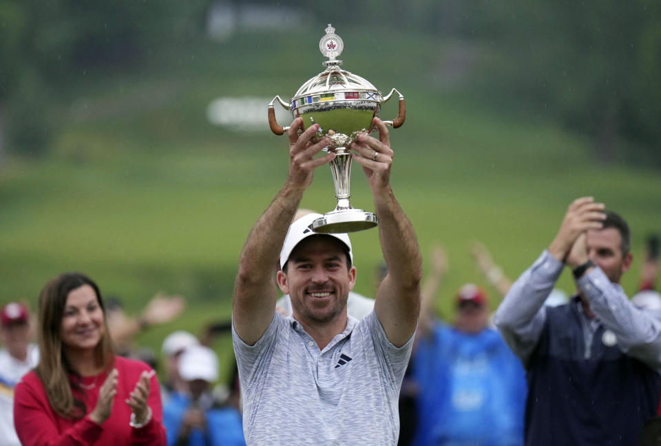 Nick Taylor, center, of Canada, holds the trophy after winning the Canadian Open golf tournament on the fourth playoff hole against Tommy Fleetwood, of the United Kingdom in Toronto, Sunday, June 11, 2023. (Nathan Denette/The Canadian Press via AP)