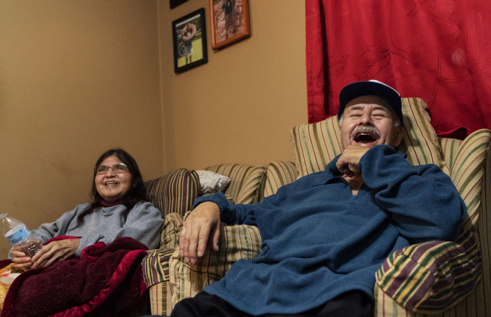 Mario Valdez, 62, right, laughs while watching television with his wife, Reyna, 52, at their home in Central Falls, R.I., Thursday, Feb. 18, 2021. "I feel happy," said Valdez, a school bus driver shortly after receiving his second and final dose. "Too many people here have COVID. It's better to be safe." (AP Photo/David Goldman)