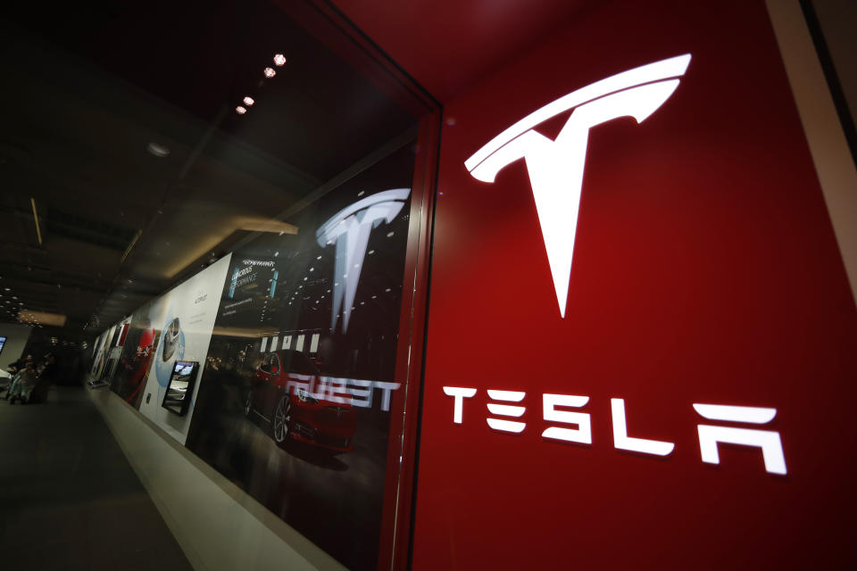 FILE - A sign bearing the company logo outside a Tesla store in Cherry Creek Mall in Denver is seen here on Feb. 9, 2019. Tesla's 2022 second-quarter profit fell 32% from record levels in the first quarter as supply chain issues and pandemic lockdowns in China slowed production of its electric vehicles. (AP Photo/David Zalubowski, File)