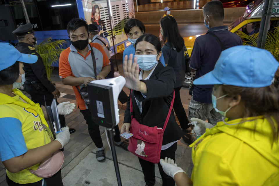 A passenger of a bus reaches to check her body temperature at roadside check point in the border of Samut Sakhon province and Bangkok in Thailand, Monday, Jan. 4, 2021. For much of 2020, Thailand had the coronavirus under control. After a strict nationwide lockdown in April and May, the number of new local infections dropped to zero, where they remained for the next six months. However, a new outbreak discovered in mid-December threatens to put Thailand back where it was in the toughest days of early 2020. (AP Photo/Gemunu Amarasinghe)