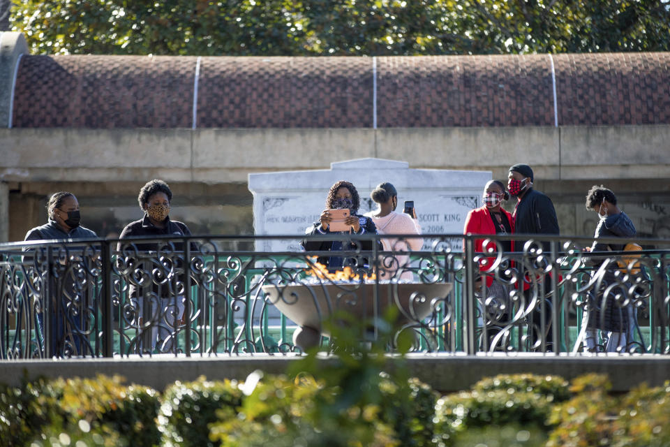 People visit the eternal flame at the tomb of Rev. Martin Luther King Jr. and his wife Coretta Scott King on Monday, Jan. 18, 2021, to celebrate the Martin Luther King Jr. holiday, in Atlanta. (AP Photo/Branden Camp)