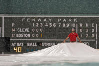 A grounds crew worker holds up the tarp covering the infield as heavy rain falls during the third inning of a baseball game between the Cleveland Guardians and the Boston Red Sox at Fenway Park, Monday, July 25, 2022, in Boston. (AP Photo/Charles Krupa)