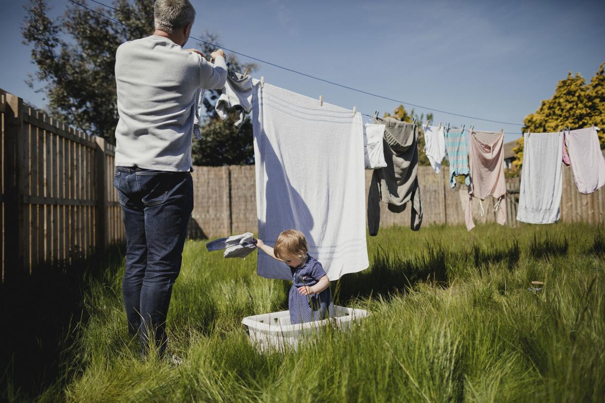mature father hanging out washing while caring for his baby daughter