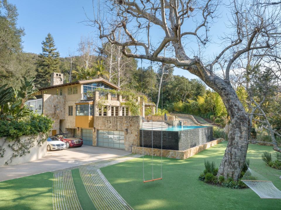 A view of the garage and the backyard that has a swing attached to a large tree