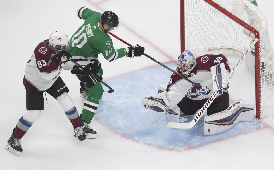 Dallas Stars' Corey Perry (10) tries to get the puck loose from Colorado Avalanche goalie Pavel Francouz (39) as Avalanche's Matt Nieto (83) defends during first period NHL qualifying round game action in Edmonton, on Wednesday, Aug. 5, 2020. (Jason Franson/The Canadian Press via AP)