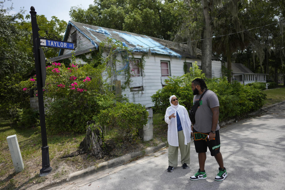 NY Nathiri, left, and Julian Johnson, who lead separate organizations working to preserve the town's heritage and culture, and boost its economy, talk together as they walk past the town's oldest remaining structure, known as the Historic Thomas House, in Eatonville, Fla., Wednesday, Aug. 23, 2023. Eatonville puts on the annual ZORA! festival to celebrate both the town's history and author Zora Neale Hurston, who grew up there and depicted a fictionalized version of it in her work. (AP Photo/Rebecca Blackwell)