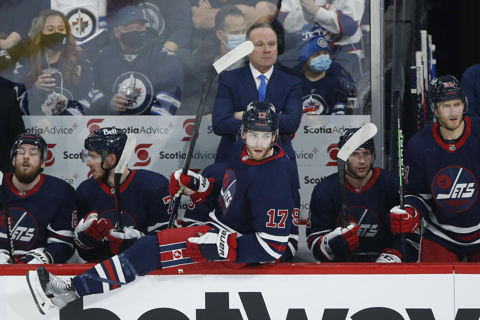 Winnipeg Jets' Adam Lowry (17) goes over the boards as his father, the new interim head coach, Dave Lowry, looks on against the Washington Capitals during the first period of an NHL hockey game Friday, Dec. 17, 2021 in Winnipeg, Manitoba. (John Woods/The Canadian Press via AP)