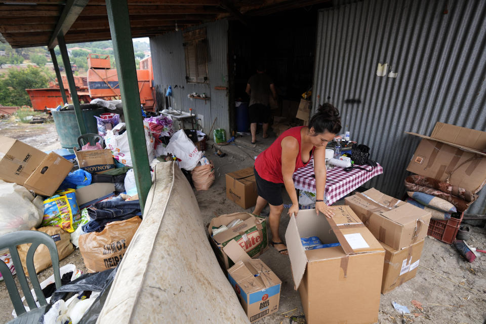 A woman stores the boxes of donated goods at Milies village on Evia island, about 181 kilometers (113 miles) north of Athens, Greece, Thursday, Aug. 12, 2021. Greek Prime Minister Kyriakos Mitsotakis says the devastating wildfires that burned across the country for more than a week amount to the greatest ecological catastrophe Greece has seen in decades. (AP Photo/Petros Karadjias)