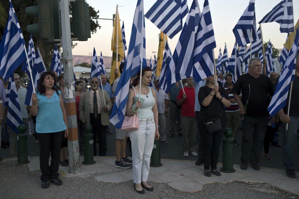 Supporter of Greece's extreme right Golden Dawn party hold Greek flags as they sing the national anthem during a rally against the construction of a mosque in Athens, Wednesday, Sept. 5, 2018. (AP Photo/Petros Giannakouris)