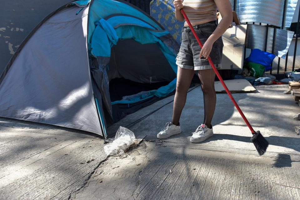 Woman sweeping street next to tents