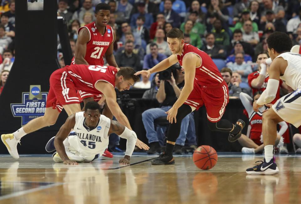 Villanova forward Darryl Reynolds (45) dives for a loose ball against Wisconsin forward Alex Illikainen (25) and guard Zak Showalter (3) during the first half of a second-round men's college basketball game in the NCAA Tournament, Saturday, March 18, 2017, in Buffalo, N.Y. Wisconsin won, 65-62. (AP Photo/Bill Wippert)