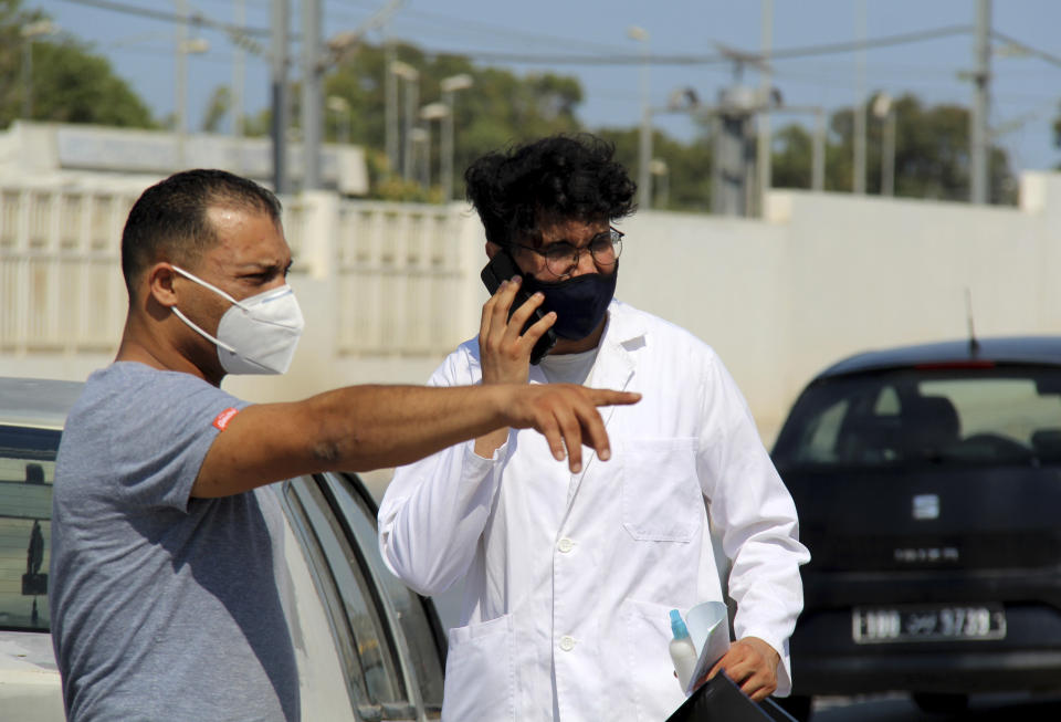 People wearing face masks to protect from COVID-19, stand outside a hospital in Tunis, Tunisia, Wednesday, July 21, 2021. Tunisia's president on Wednesday ordered the military to take over management of the national COVID-19 pandemic response, as the country fights one of Africa's worst outbreaks. (AP Photo/Hassene Dridi)