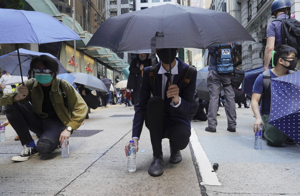 Protesters with umbrellas and bottles of water to douse tear gas canisters form up during confrontation with police in Hong Kong on Monday, Nov. 11, 2019. A protester was shot by police Monday in a dramatic scene caught on video as demonstrators blocked train lines and roads during the morning commute. (AP Photo/Vincent Yu)