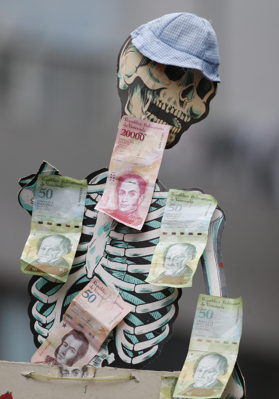 A skeleton is covered with Venezuelans Bolivar bills to symbolize the devaluation of the currency and hunger, during an opposition march in Caracas, Venezuela, Tuesday, March 10, 2020. U.S.-backed Venezuelan political leader Juan Guaido led the march aimed at retaking the National Assembly legislative building, which opposition lawmakers have been blocked from entering, but the march was blocked by police early in its route. (AP Photo/Ariana Cubillos)