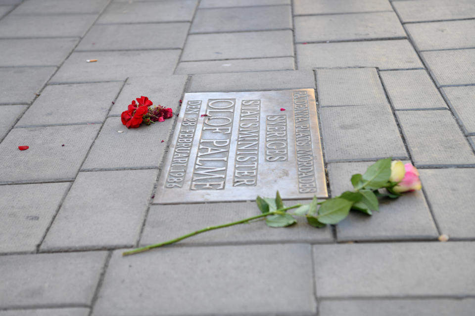 Flowers are placed by a memorial plaque showing the place where Swedish Prime Minister Olof Palme was shot dead in February 1986, in Stockholm, Sweden, Wednesday, June 10, 2020. Sweden on Wednesday dropped its investigation into the unsolved murder of former Swedish Prime Minister Olof Palme, who was shot dead 34 years ago in downtown Stockholm because the main suspect, Stig Engstrom, had died in 2000. (Fredrik Sandberg/TT via AP)