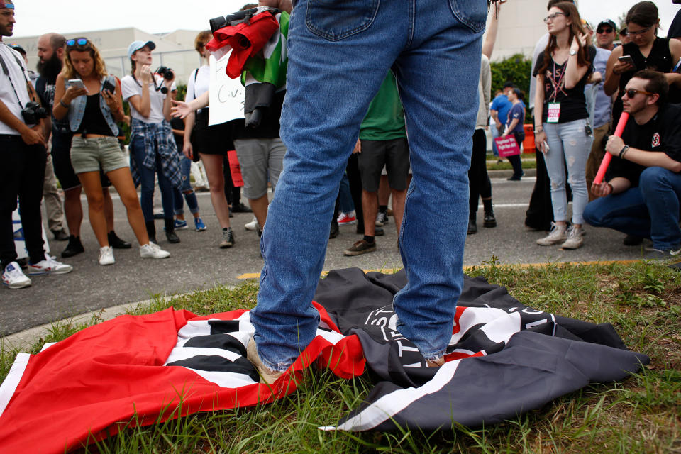 <p>A man stands on a Nazi flag and an ANTIFA flag as demonstrators gather near the site of a planned speech by white nationalist Richard Spencer, who popularized the term ‘alt-right’, at the University of Florida campus on Oct.19, 2017 in Gainesville, Fla. (Photo: Brian Blanco/Getty Images) </p>