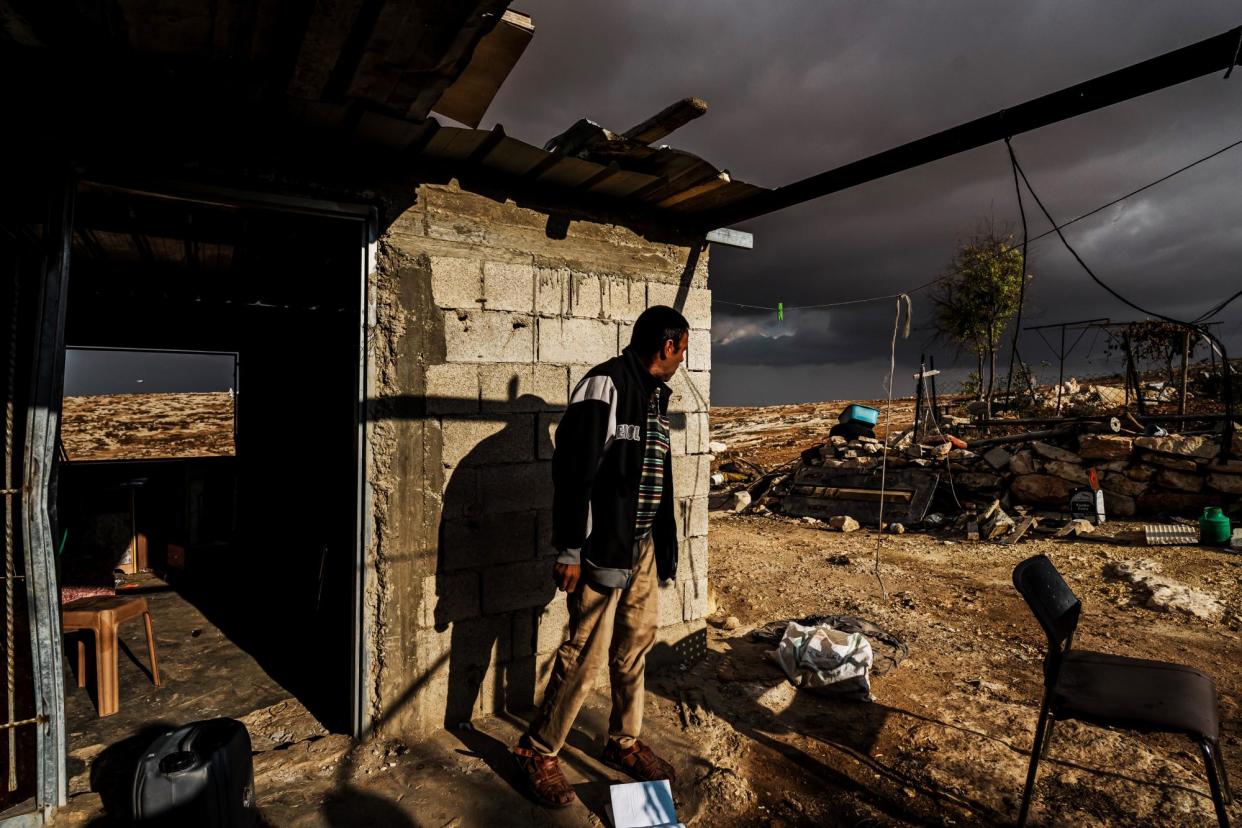 <span>A Palestinian man inspects the damage to his home and keeps an eye out for Israeli settlers, in Shaeb al-Botum, occupied West Bank, on 15 November 2023.</span><span>Photograph: Marcus Yam/Los Angeles Times/Getty Images</span>