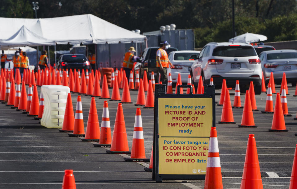 Motorists are screened as they line up for a COVID-19 vaccine appointment at the mass vaccination site at the parking lot of L.A. County Office of Education headquarters in Downey, Calif., Wednesday, Feb. 3, 2021. California continues to change up its coronavirus vaccine system with its top health officer on Tuesday suggesting revisions to who's next in line for still-scarce doses as officials put together a still-murky statewide distribution and data collection system aimed at ensuring speed and equity. (AP Photo/Damian Dovarganes)