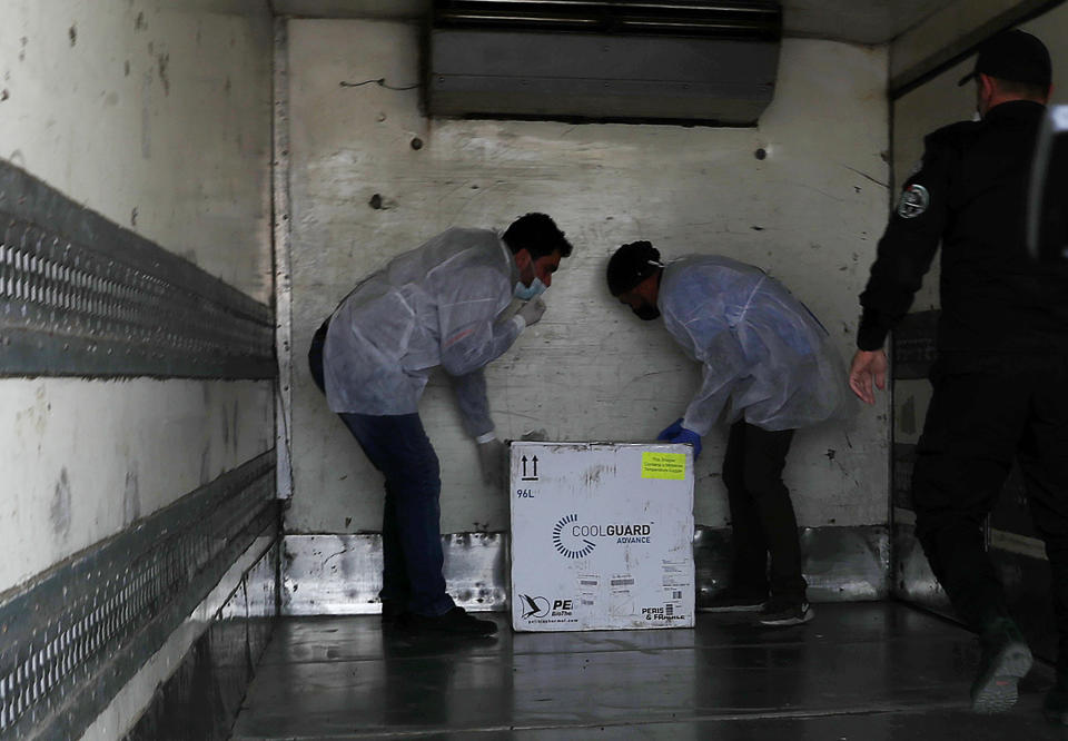 Medics check a shipment of the Russian Sputnik V vaccine inside a truck at the Kerem Shalom border crossing, in Rafah, Gaza Strip, Wednesday, Feb. 17, 2021. The Palestinian Authority said Wednesday that it dispatched the first shipment of coronavirus vaccines to the Hamas-ruled Gaza Strip, two days after accusing Israel of preventing it from sending the doses amid objections from some Israeli lawmakers. (AP Photo/Adel Hana)