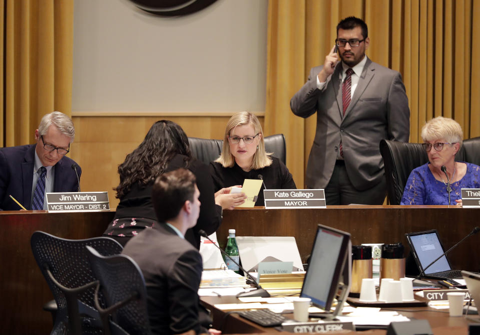 Phoenix Mayor Kate Gallego, center, convenes a session inside City Council chambers, Wednesday, June 19, 2019, in Phoenix, to hear people angered by a video of Phoenix officers who pointed guns and yelled obscenities at a black family they suspected of shoplifting. Speakers called on the council to fire the officers involved in the videotaped incident and to create a board of civilians to oversee changes in department procedures. (AP Photo/Matt York)