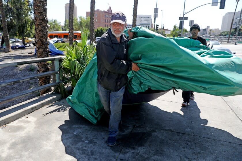 LOS ANGELES, CA - APRIL 12: Harvey Hernandez, 58, homeless for 22 years, moves his tent and belongings back to the sidewalk after the City of Los Angeles Sanitation Department powerwashed along Arcadia St. in downtown on Tuesday, April 12, 2022 in Los Angeles, CA. Section 41.18 of the Los Angeles Municipal Code (LAMC) makes it illegal to 