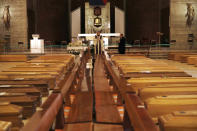 FILE - In this March 28, 2020 file photo, Don Marcello Crotti, left, blesses the coffins with Rev. Mario Carminati in the San Giuseppe church in Seriate, near Berganom, Italy. If there is anything the Rev. Mario Carminati and the traumatized residents of Italy’s Bergamo province remember about the worst days of the coronavirus outbreak, it’s the wail of ambulance sirens piercing the silence of lockdown. (AP Photo/Antonio Calanni, file)