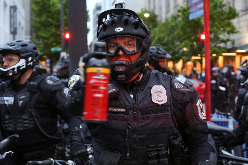 Police officer pointing pepper spray cannister