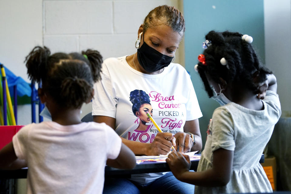 Laiah Collins, 4, left, and Charisma Edwards, 5, right, work with Davetra Richardson (STLS) in a classroom at Chalmers Elementary school in Chicago, Wednesday, July 13, 2022. America's big cities are seeing their schools shrink, with more and more of their schools serving small numbers of students. Those small schools are expensive to run and often still can't offer everything students need (now more than ever), like nurses and music programs. Chicago and New York City are among the places that have spent COVID relief money to keep schools open, prioritizing stability for students and families. But that has come with tradeoffs. And as federal funds dry up and enrollment falls, it may not be enough to prevent districts from closing schools. (AP Photo/Nam Y. Huh)