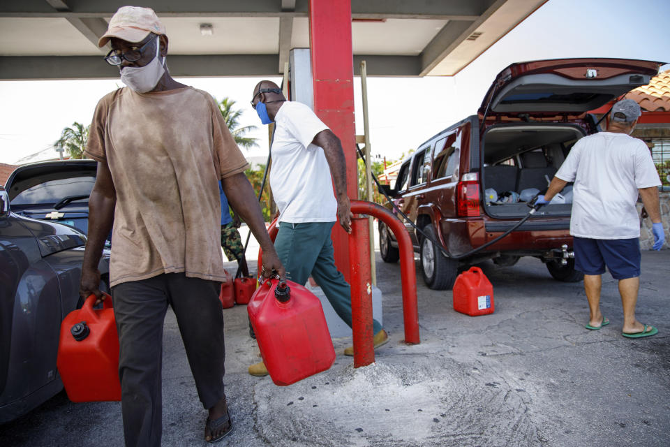 A resident walks with containers filled with gasoline at Cooper's gas station before the arrival of Hurricane Isaias in Freeport, Grand Bahama, Bahamas, Friday, July 31, 2020. (AP Photo/Tim Aylen)