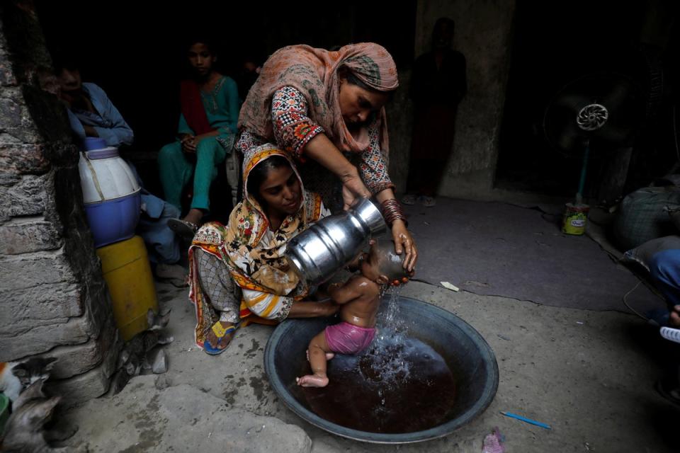 Rehmat, 30, helps Razia, 25, bathe her six-month-old daughter Tamanna to cool off during a heatwave (Reuters)
