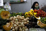 A vegetable vendor wears a mask amid the COVID-19 pandemic as the local government allows the reopening of markets and street fairs in Brasilia, Brazil, Friday, July 3, 2020. (AP Photo/Eraldo Peres)