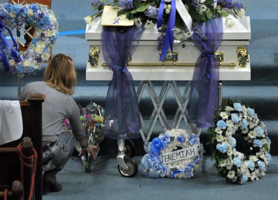 A woman places flowers in front of the casket before the start of the funeral for five-year-old Jeremiah Oliver at Rollstone Congregational Church in Fitchburg, Mass., on Saturday, May 3, 2014. Oliver disappeared in September 2013 and was found dead along Interstate 190 in Sterling, Mass., in April. (AP Photo/Worcester Telegram & Gazette, Paul Kapteyn)