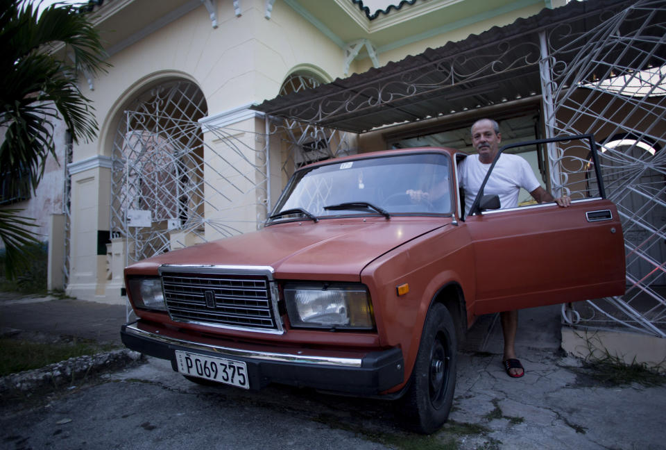 Leandro Cueto poses for a portrait with his car, a Russian 1986 Lada, at his home in Havana, Cuba, Tuesday, Oct. 6, 2019. Cueto said he bought the car new in 1986, which requires repairs every five years, and has repainted it once. (AP Photo/Ismael Francisco)