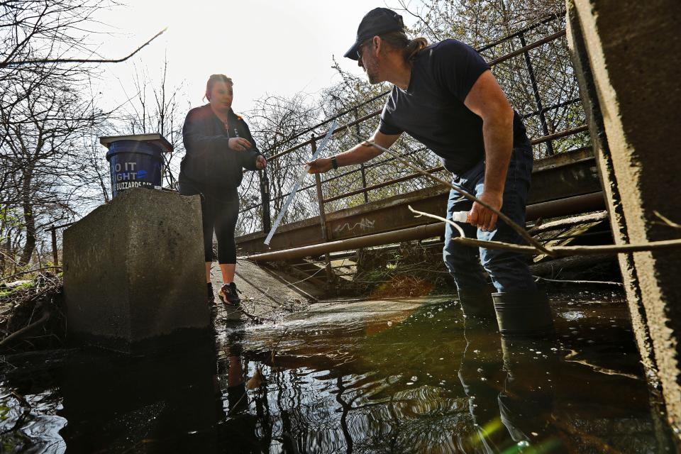 Dan Goulart and Virgina Parker test the waters of Buttonwood Brook as part of the Buzzards Bay Coalition project to improve water quality and restore natural habitat in the brook and Apponagansett Bay.
