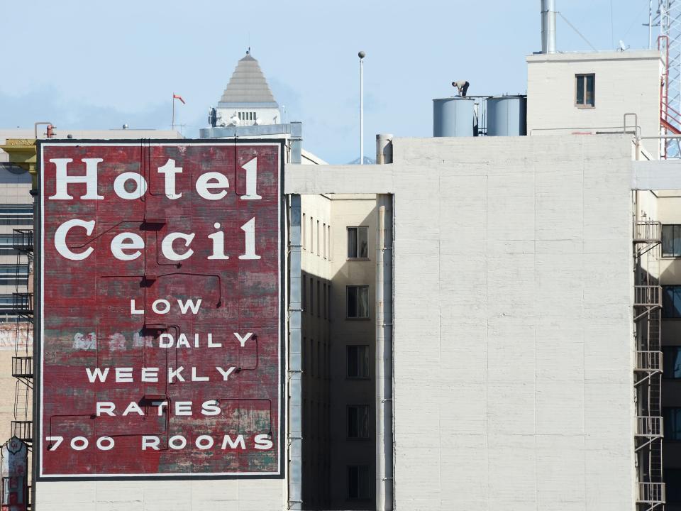 Building showing red sign reading "Hotel Cecil Low Daily Weekly Rates 700 Rooms" and an opening in the middle of the building.