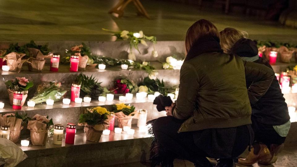 Zwei Frauen legen Blumen und Kerzen bei der Gedenkfeier für eine 17-Jährige in der Nikolaikirche auf die Stufen vor dem Altar. Foto: Malte Christians