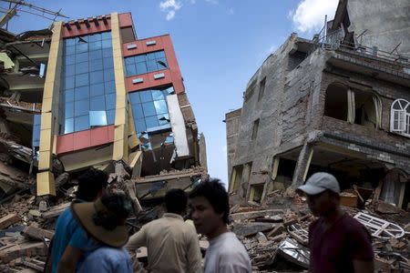 People walk past a collapsed building after a fresh 7.3 earthquake struck, in Kathmandu, Nepal, May 12, 2015. REUTERS/Athit Perawongmetha