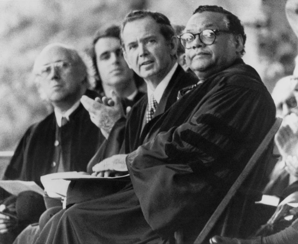 FILE - In this Monday, May 17, 1976 file photo, U.S. Dept. of Transportation Secretary William T. Coleman Jr., right, and Michigan Gov. William G. Milliken, second from right, sit on the platform during Commencement ceremonies at Yale University in New Haven, Conn. William G. Milliken, Michigan’s longest-serving governor who established a record of environmental conservation and bipartisan cooperation that made him popular among Republicans and Democrats, died Friday, Oct. 18, 2019 at age 97, a family spokesman said. (AP Photo/Bob Child, File)