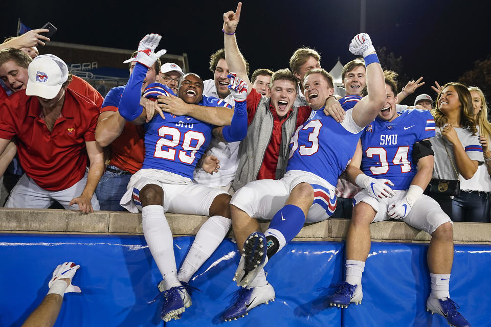 FILE - SMU cornerback Justin Guy-Robinson (29), place kicker Kevin Miles (93) and safety Brice Madison (34) celebrate with fans after a 37-20 victory over Tulane in an NCAA football game at Ford Stadium in Dallas, Saturday, Nov. 30, 2019. Next year, the Big Ten will have 18 schools, the Big 12 and SEC 16 each and the ACC 17 football-playing members, including SMU in Dallas.(Smiley N. Pool/The Dallas Morning News via AP, File)