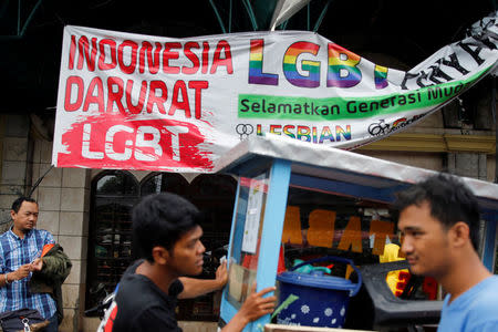 A street vendor walks past a banner reading 'Indonesia LGBT Emergency' in front a mosque in Jakarta, Indonesia, January 25, 2018. REUTERS/Beawiharta