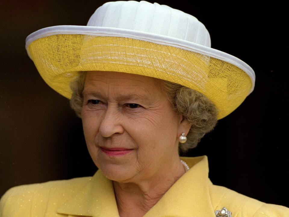 the queen in 1997 wearing a yellow hat and suit